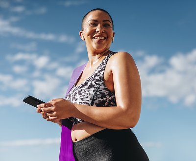 Woman smilling outside in the sun using mobile phone